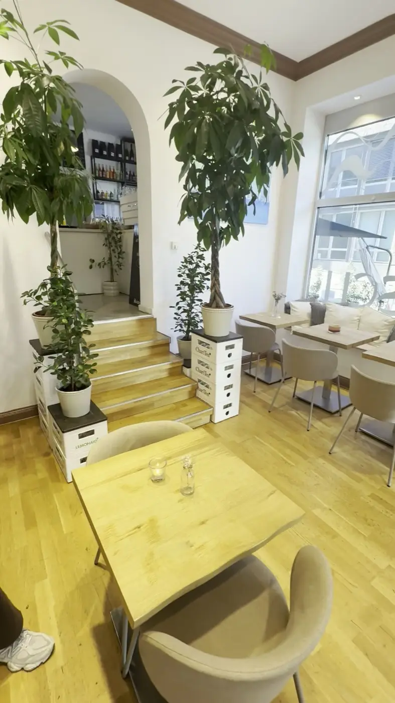 Salon mit Holztischen, Treppe und Pflanzen